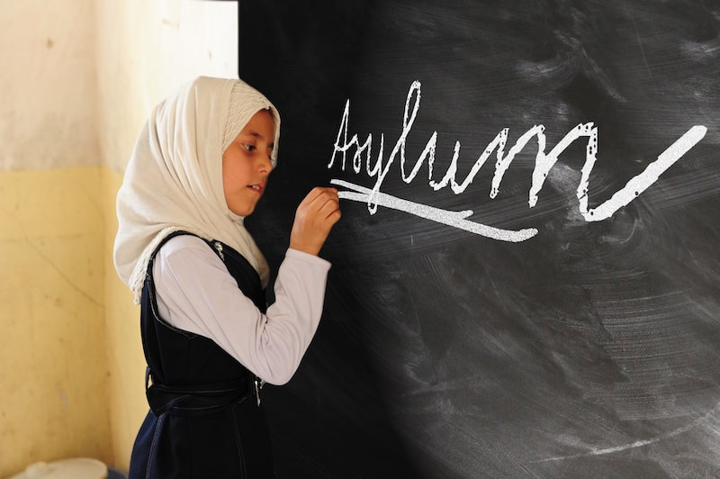 picture of a girl writing word asylum on blackboard in classroom credit pixy.org