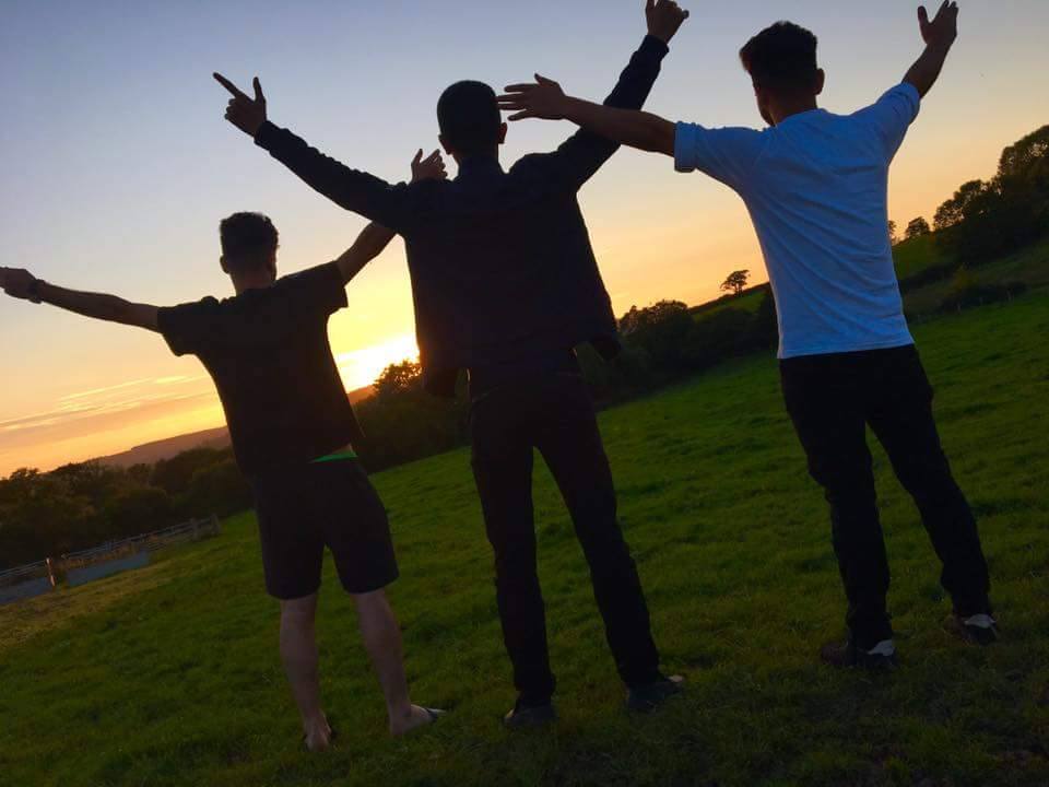 picture of three young people back to camera, arms in the air, silhouetted against sunset sky image © Kayte / Elmbridge CAN